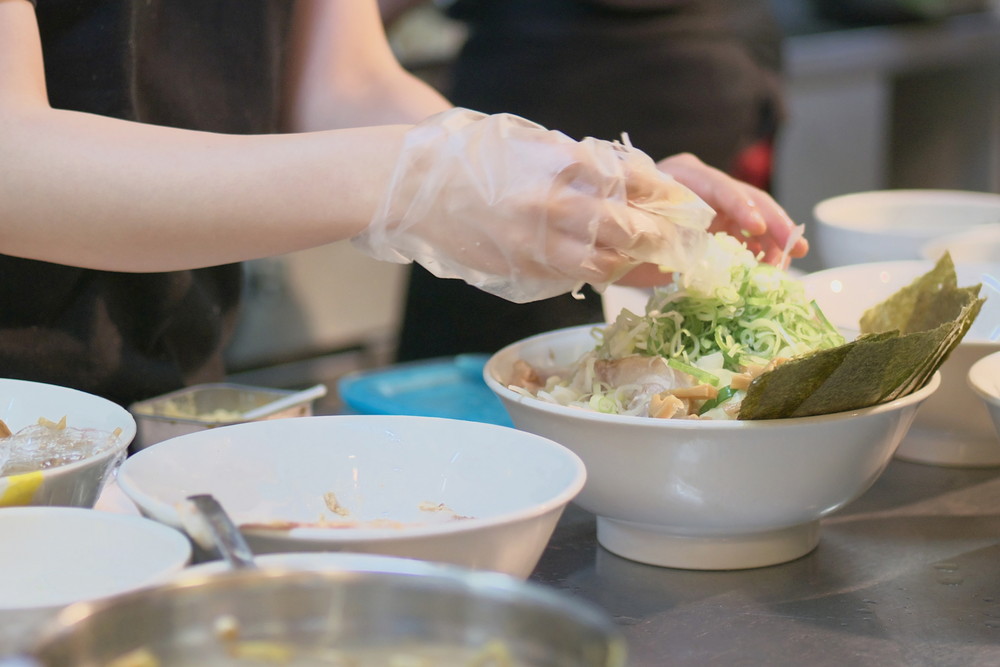 調理用手袋をつけてサラダを盛り付ける手元