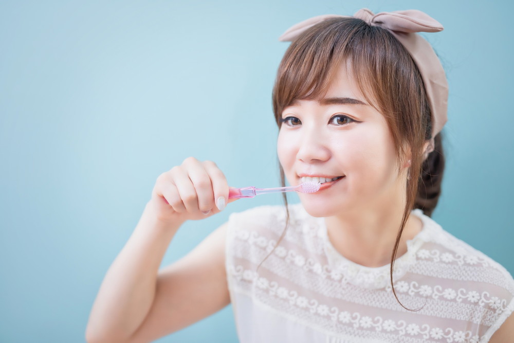 電動歯ブラシで歯を磨く女性